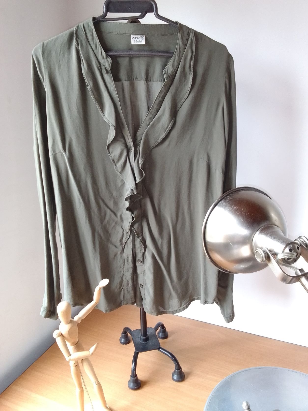 Blusa verde seco con volante medio al cuello.